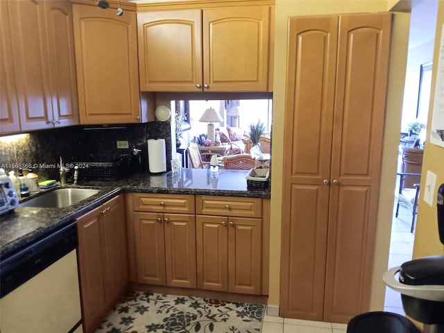 kitchen featuring dark stone counters, sink, decorative backsplash, light tile patterned floors, and white dishwasher