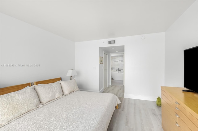 bedroom with light wood-type flooring and ensuite bathroom