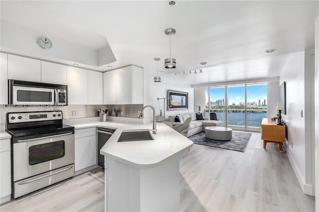 kitchen with sink, white cabinetry, kitchen peninsula, a water view, and appliances with stainless steel finishes