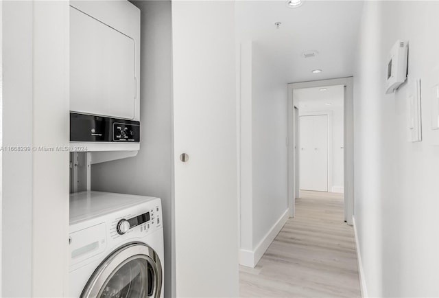 laundry area with light hardwood / wood-style floors and stacked washer and clothes dryer