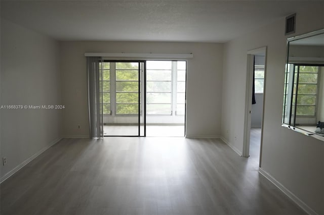 unfurnished room with wood-type flooring and a textured ceiling