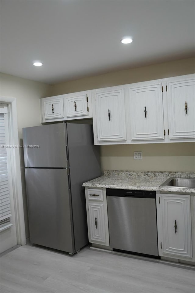 kitchen featuring light hardwood / wood-style flooring, appliances with stainless steel finishes, sink, and white cabinetry