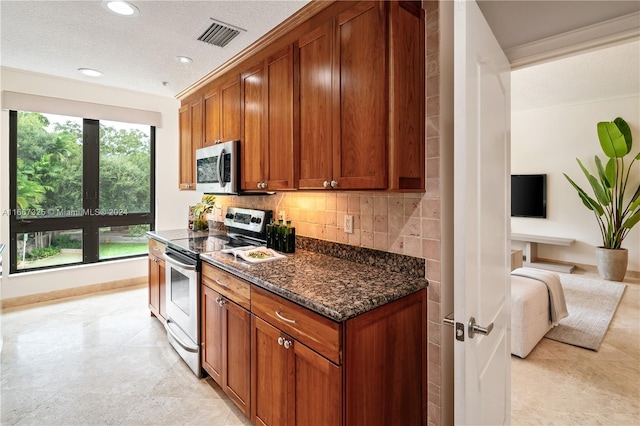 kitchen featuring dark stone counters, stainless steel appliances, a textured ceiling, and tasteful backsplash