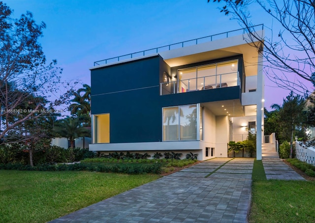 view of front of property with a balcony and a lawn