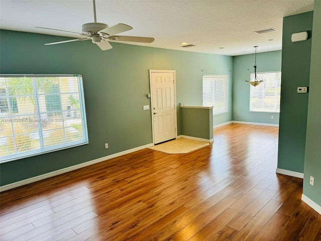 empty room featuring ceiling fan, a textured ceiling, and light hardwood / wood-style floors