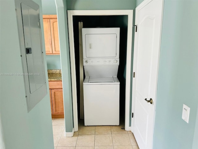 clothes washing area with stacked washer and clothes dryer, electric panel, and light tile patterned floors