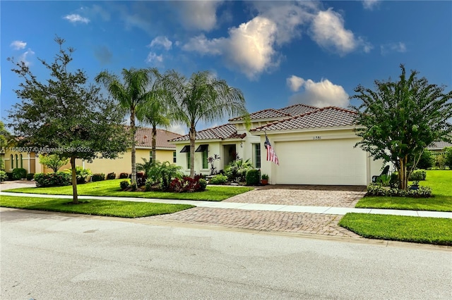 mediterranean / spanish-style house with an attached garage, a tiled roof, stucco siding, a front yard, and driveway