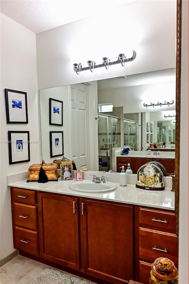 bathroom with vanity, a shower with shower door, a textured ceiling, and tile patterned floors