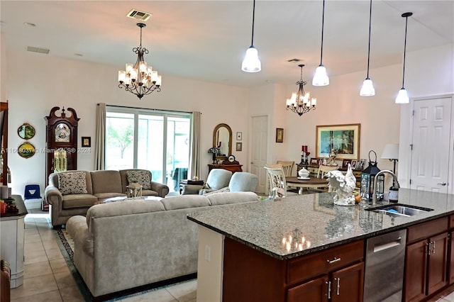 kitchen with hanging light fixtures, an island with sink, stone countertops, sink, and a chandelier