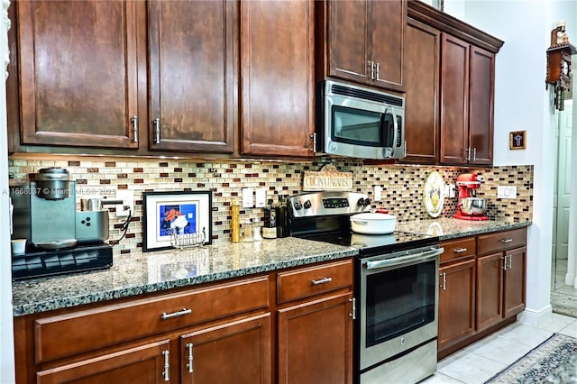 kitchen featuring stainless steel appliances, dark brown cabinetry, decorative backsplash, light tile patterned floors, and light stone countertops