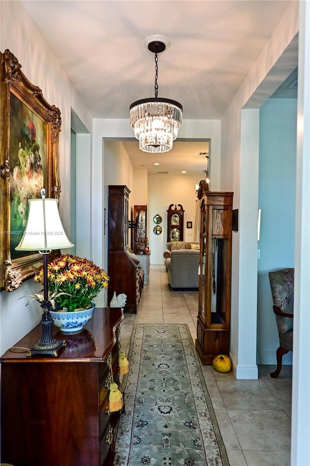 hall featuring light tile patterned floors, a chandelier, and baseboards
