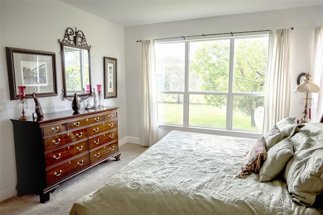 bedroom with light colored carpet, multiple windows, and baseboards