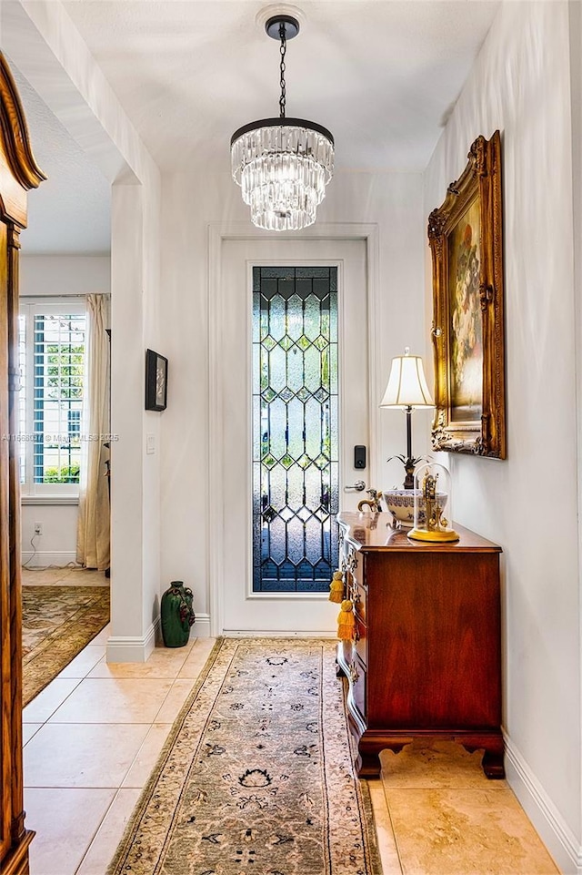 tiled entrance foyer featuring a chandelier and baseboards