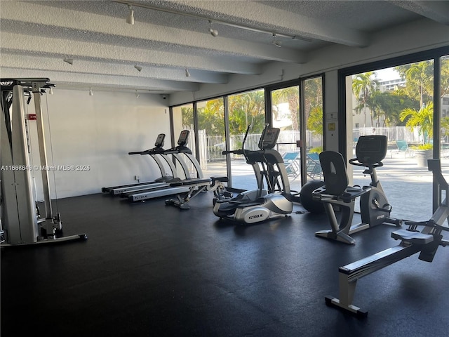 exercise room featuring track lighting and a textured ceiling