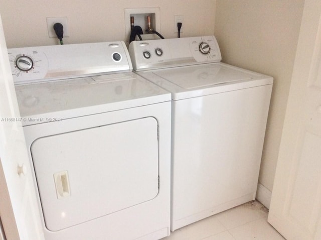 clothes washing area featuring light tile patterned flooring and washing machine and dryer