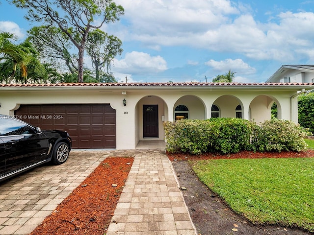 mediterranean / spanish-style house with a garage and a front lawn