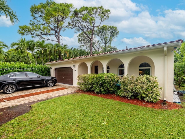 mediterranean / spanish-style house featuring a front yard and a garage