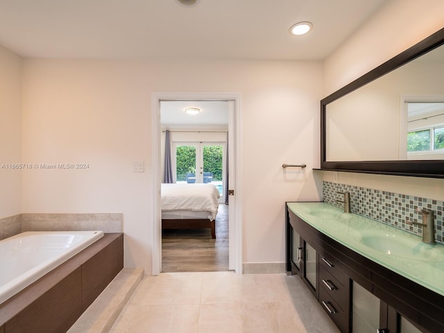 bathroom with vanity, plenty of natural light, a bath, and backsplash