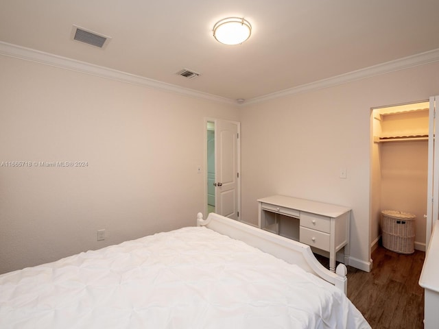 bedroom featuring a closet, a walk in closet, ornamental molding, and dark hardwood / wood-style floors