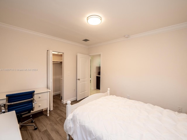 bedroom featuring ornamental molding, a spacious closet, light hardwood / wood-style flooring, and a closet