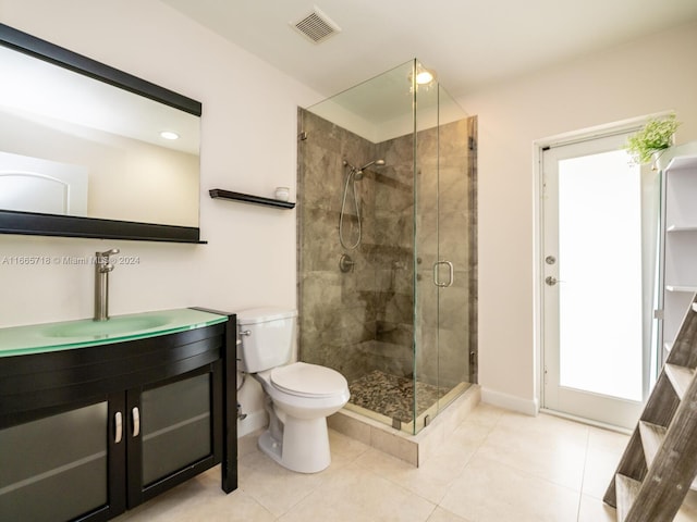 bathroom featuring toilet, vanity, tile patterned flooring, and a shower with shower door