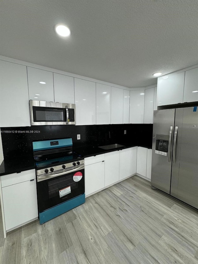 kitchen with light hardwood / wood-style flooring, stainless steel appliances, and white cabinetry