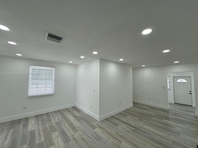 empty room featuring a textured ceiling and light hardwood / wood-style flooring