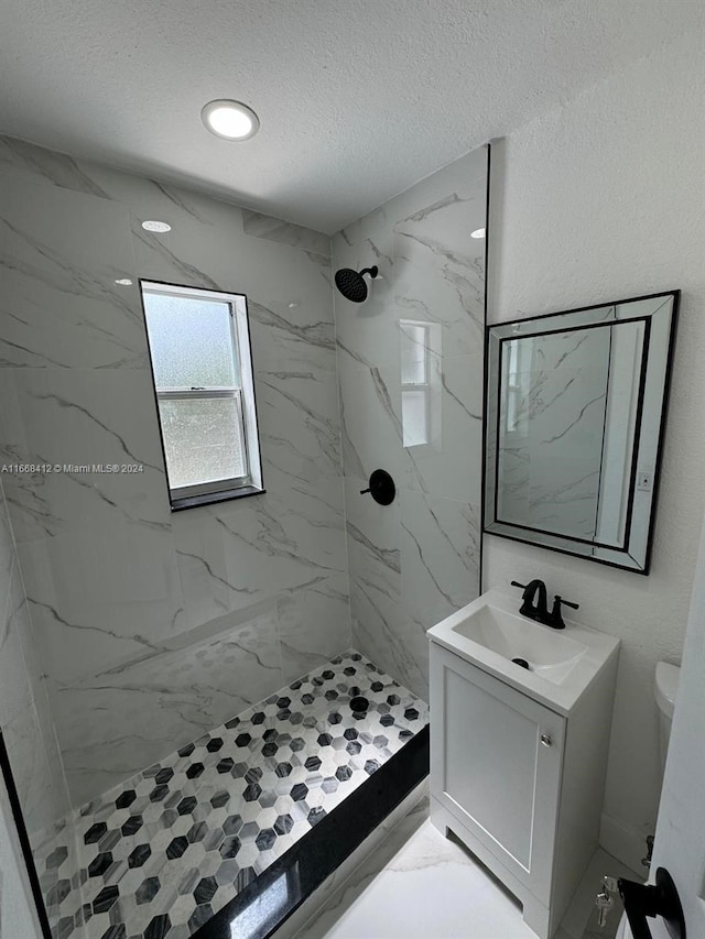 bathroom featuring vanity, toilet, a textured ceiling, and tiled shower