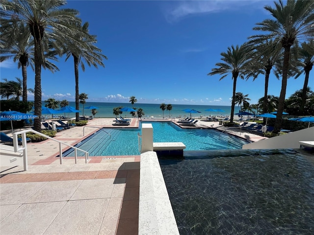 view of pool with a patio and a water view