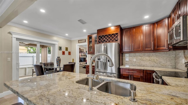 kitchen with appliances with stainless steel finishes, ornamental molding, and light stone countertops