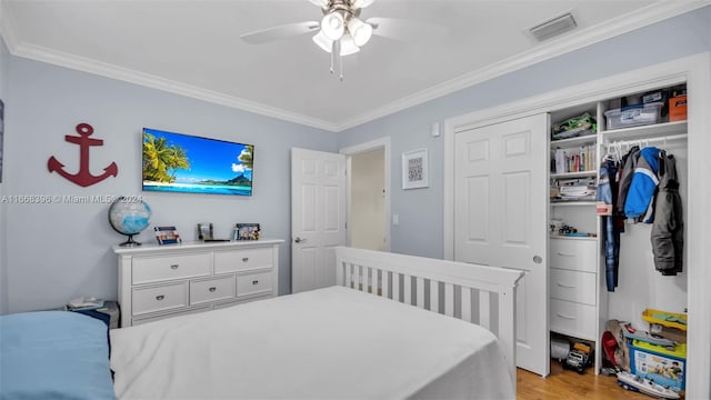 bedroom featuring ceiling fan, a closet, light wood-type flooring, and crown molding