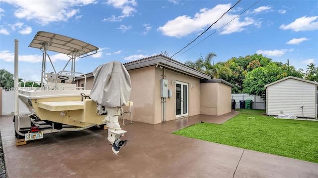 back of house with a lawn, a storage unit, and a patio area