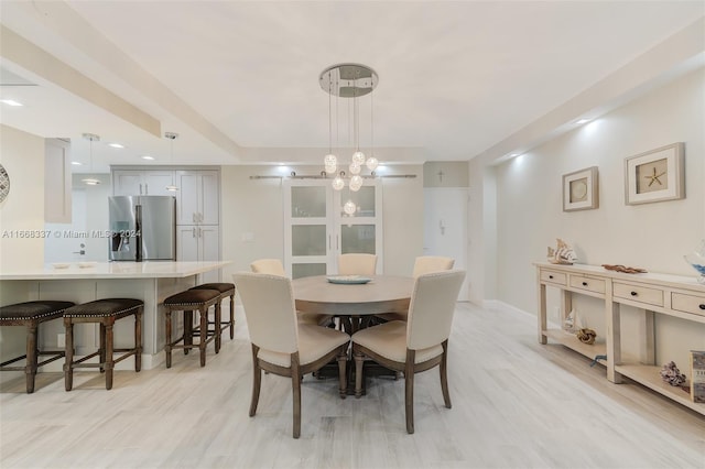 dining area featuring light wood-type flooring and an inviting chandelier