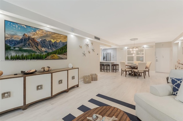 living area with visible vents, light wood finished floors, and a chandelier