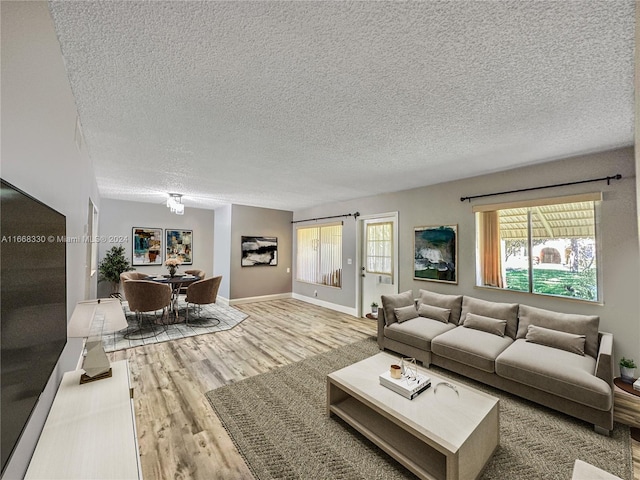 living room featuring a textured ceiling, light hardwood / wood-style floors, and a wealth of natural light