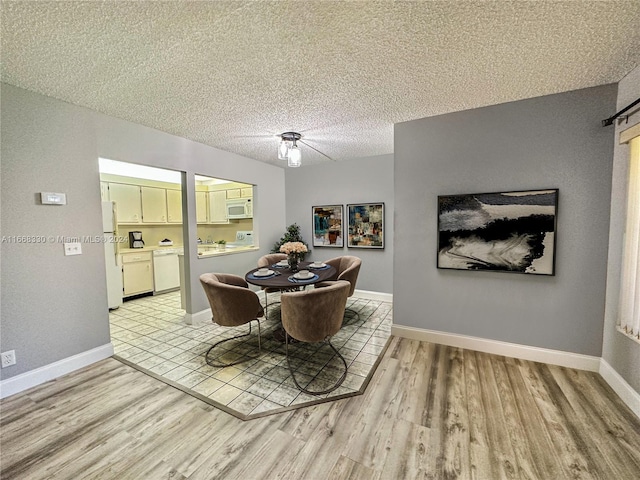 dining space with light wood-type flooring, ceiling fan, and a textured ceiling