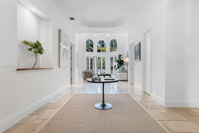 corridor with crown molding and a raised ceiling