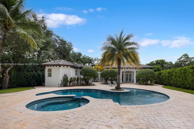 view of swimming pool with a patio, an in ground hot tub, french doors, and an outbuilding