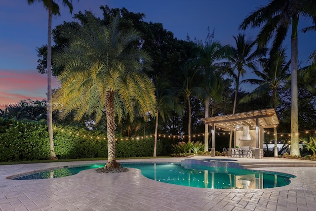 pool at dusk featuring an in ground hot tub, a patio area, and a pergola