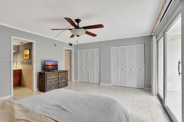 tiled bedroom with a textured ceiling, two closets, ceiling fan, and ensuite bathroom