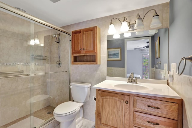 bathroom with ceiling fan, vanity, tile walls, toilet, and a shower with door