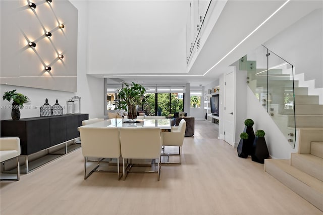 dining area featuring light hardwood / wood-style flooring and a high ceiling