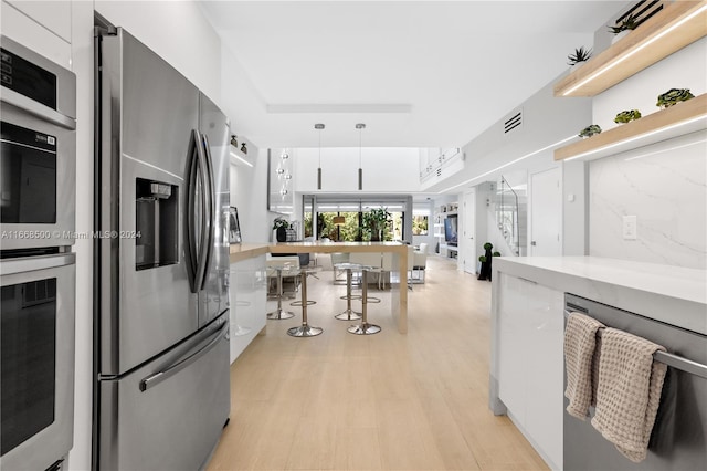 kitchen featuring stainless steel appliances, white cabinets, and light hardwood / wood-style flooring