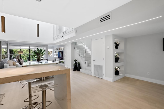 kitchen featuring a high ceiling, a kitchen bar, and light wood-type flooring