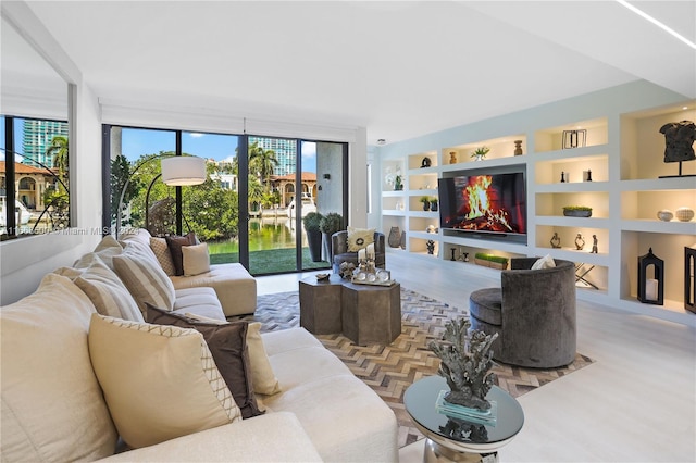 living room featuring a fireplace, expansive windows, built in shelves, and hardwood / wood-style flooring