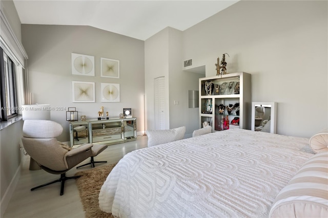 bedroom featuring hardwood / wood-style flooring, lofted ceiling, and a closet