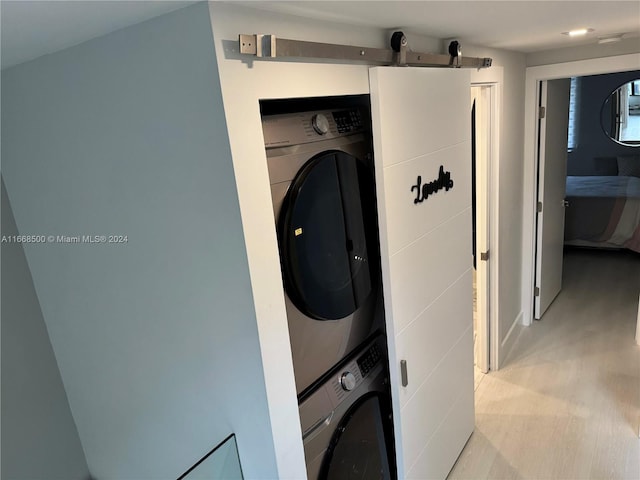 clothes washing area featuring stacked washer / dryer and light hardwood / wood-style floors