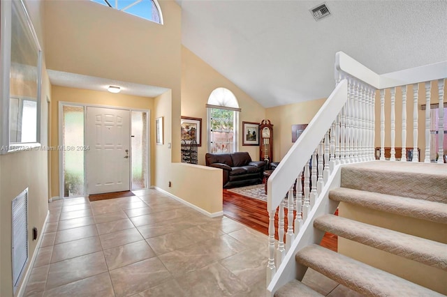 entrance foyer with plenty of natural light, high vaulted ceiling, hardwood / wood-style floors, and a textured ceiling