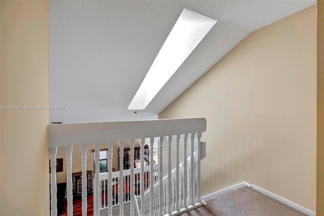 hallway featuring vaulted ceiling with skylight and carpet