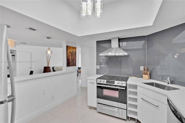 kitchen with sink, wall chimney exhaust hood, decorative light fixtures, white cabinets, and appliances with stainless steel finishes